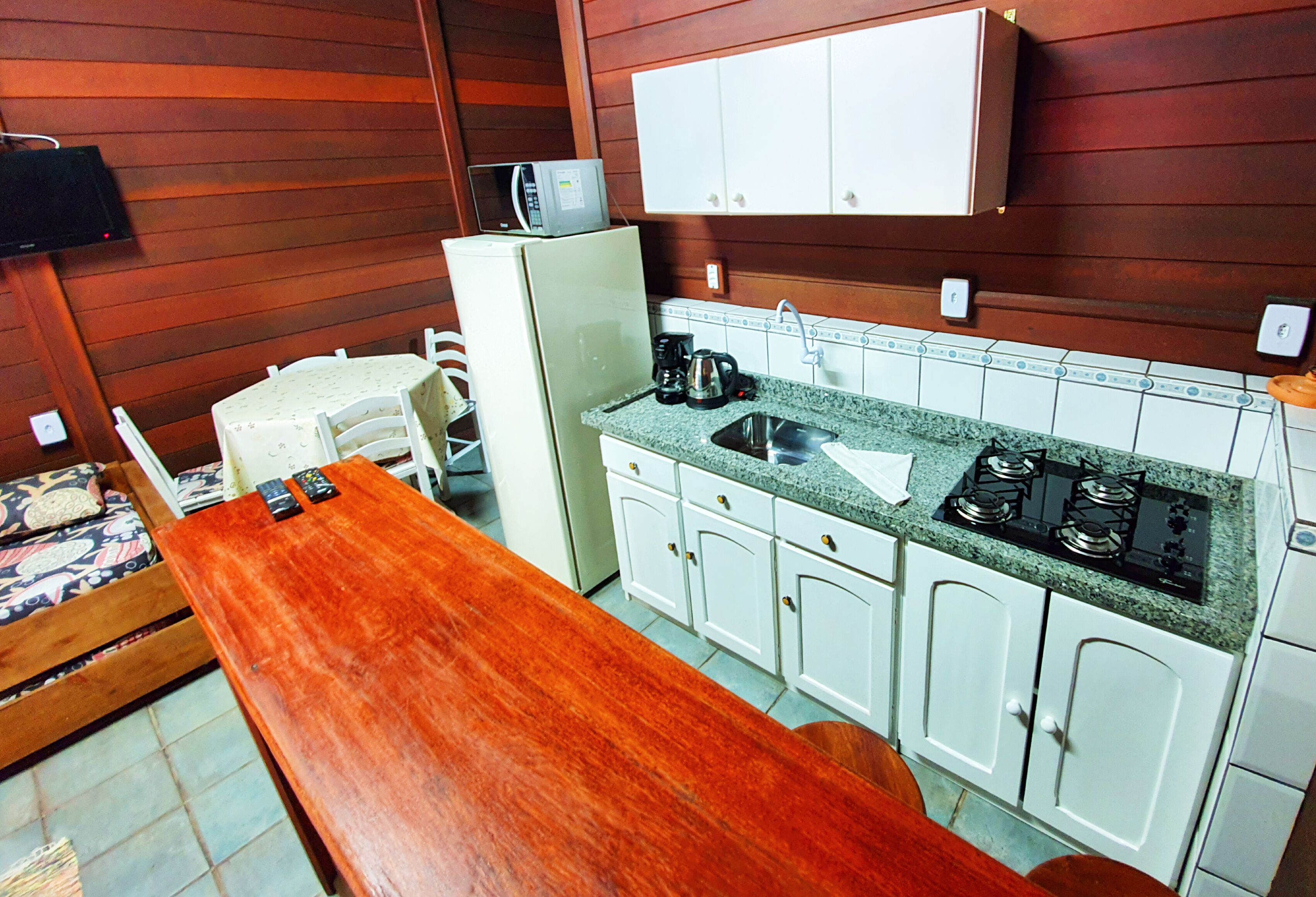 Une cuisine compacte avec une table en bois, des placards blancs, un four à micro-ondes et une cuisinière.