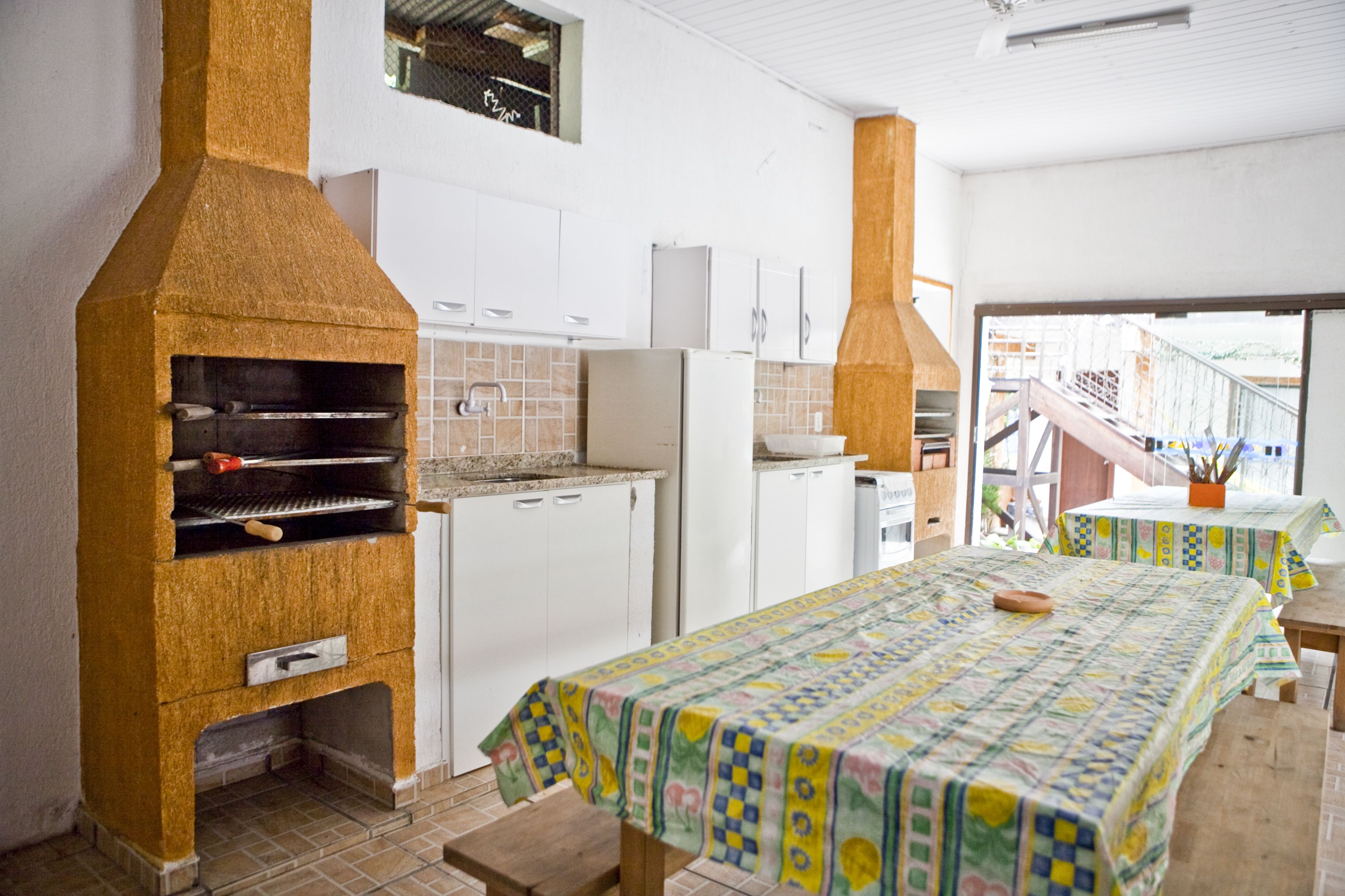Cocina compacta con horno integrado, armarios blancos y comedor con mesa y bancos.