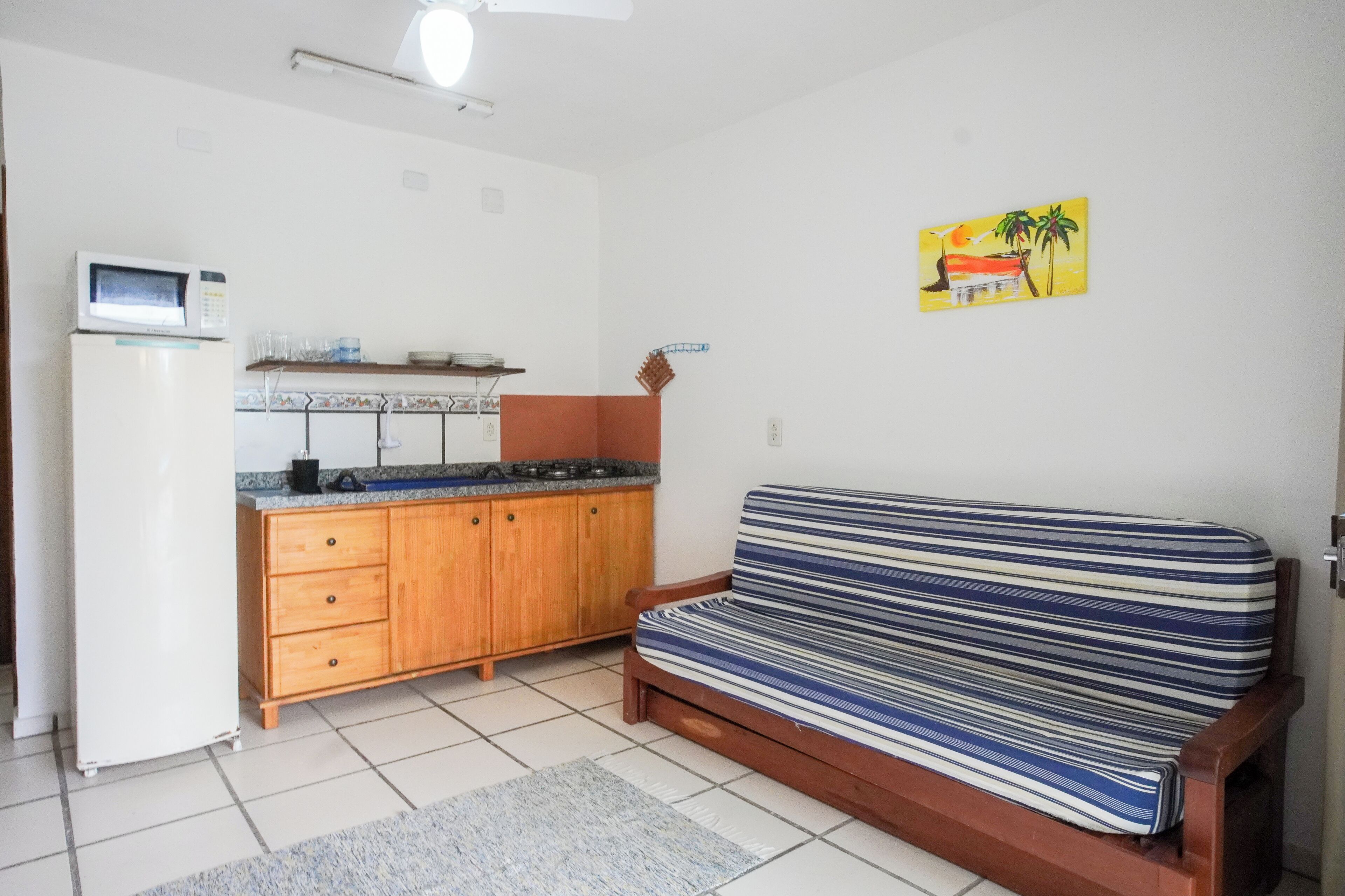 Ett kompakt bostadsutrymme med ett litet kök, en soffa och en liten matta.