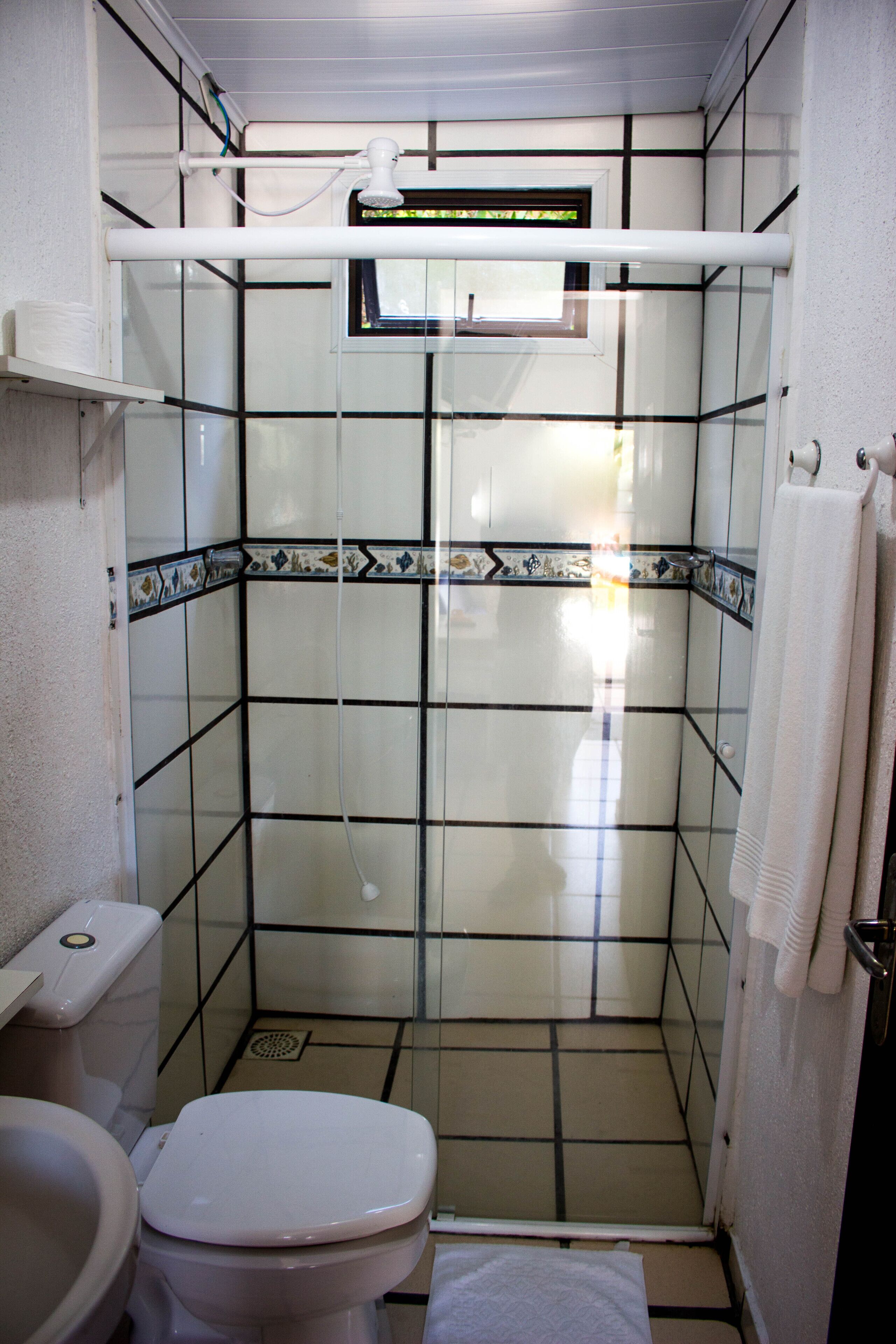 A small bathroom with a toilet, a shower stall, and a sink.