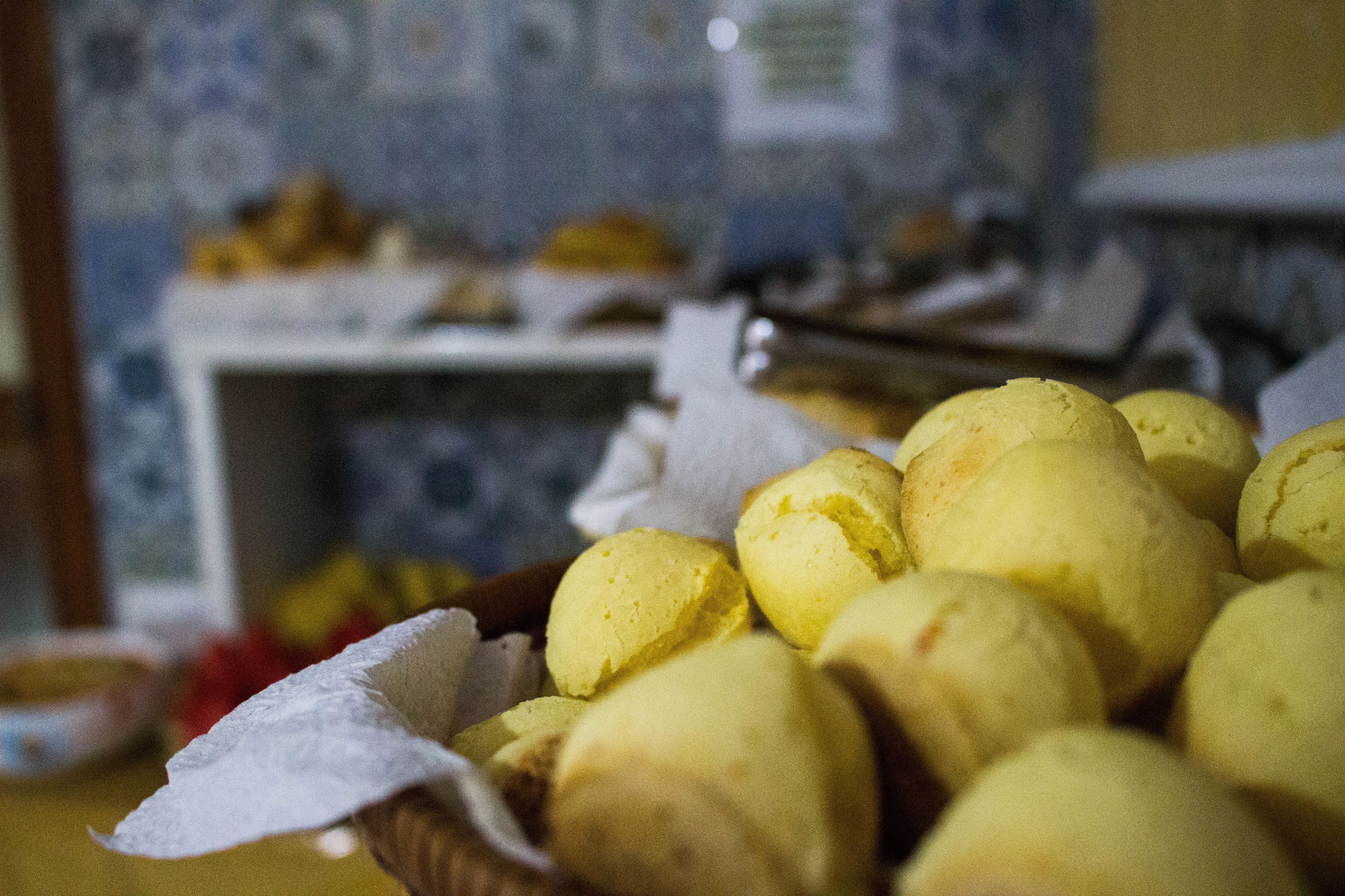 A basket of yellow doughnuts on a table with a tiled backsplash in the background.