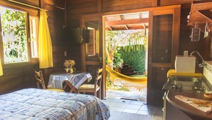 A bedroom with a bed, a small table with a vase, a chair, and a hammock. - Pousada Don Pablo (Bombinhas)