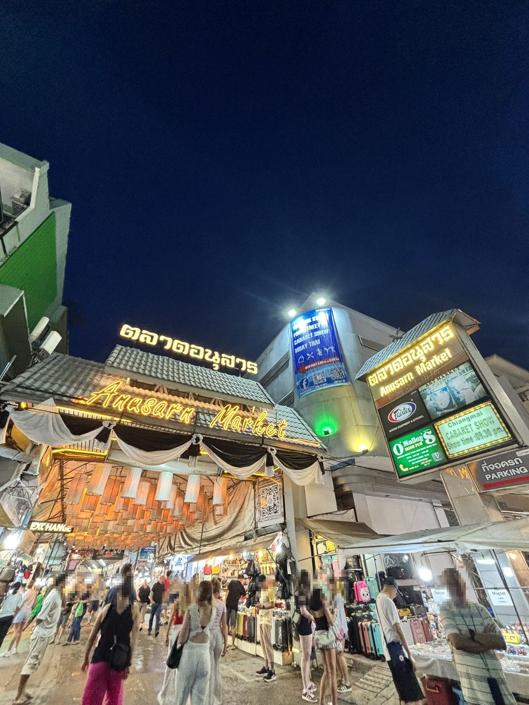 A market area with a prominent building featuring a neon sign and a large digital display.