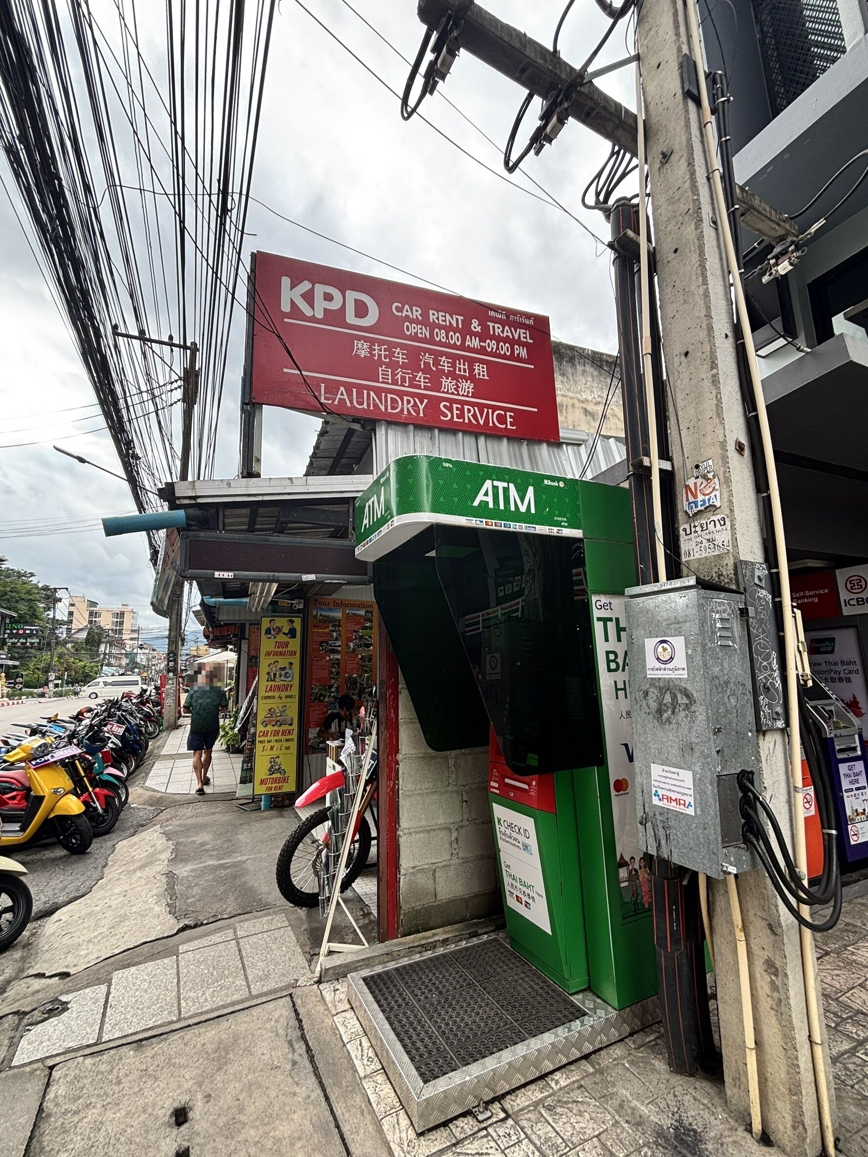 A KPD car rental and travel service, an ATM, and a motorcycle rental shop.
