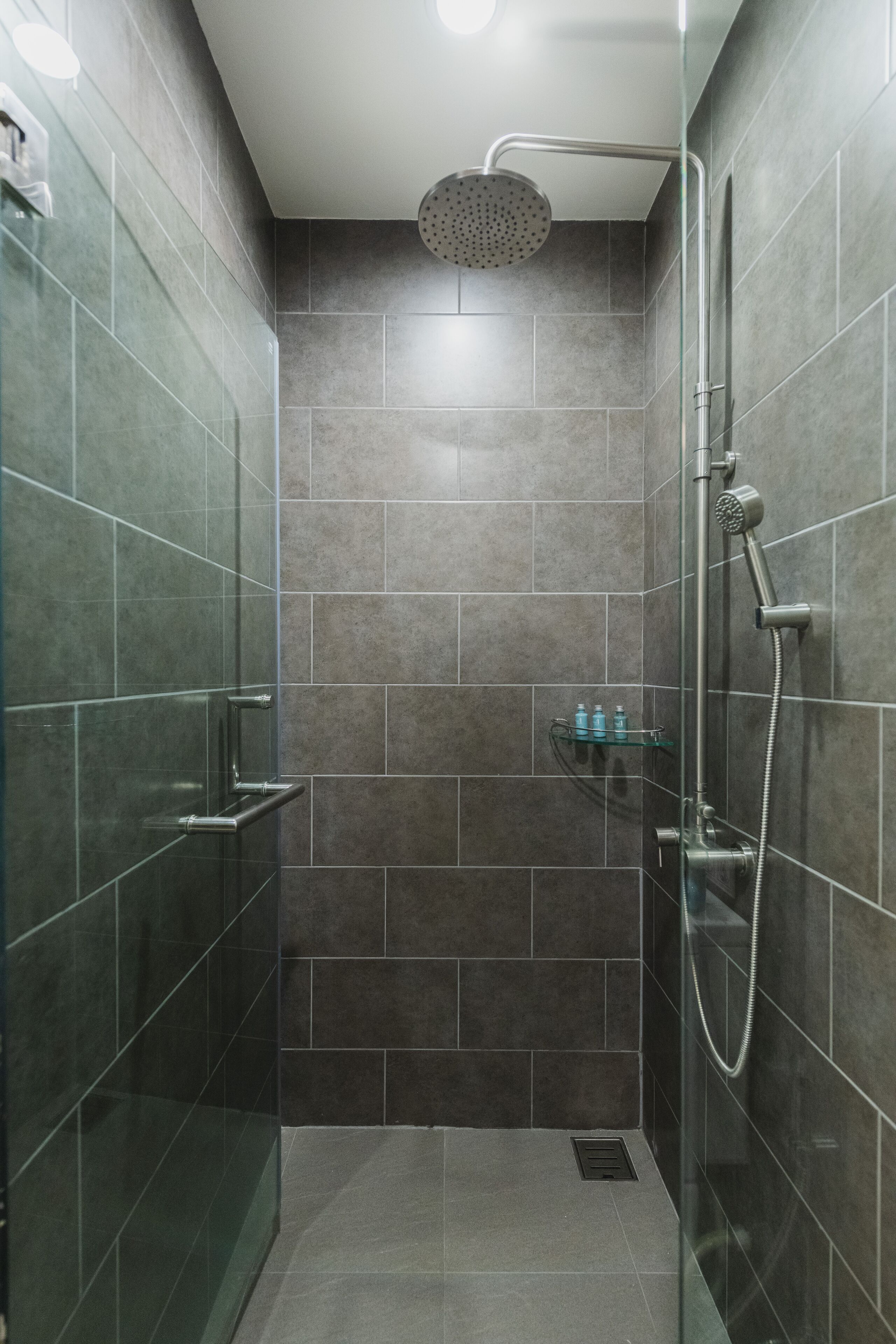 A modern shower with a handheld showerhead and a wall-mounted faucet.
