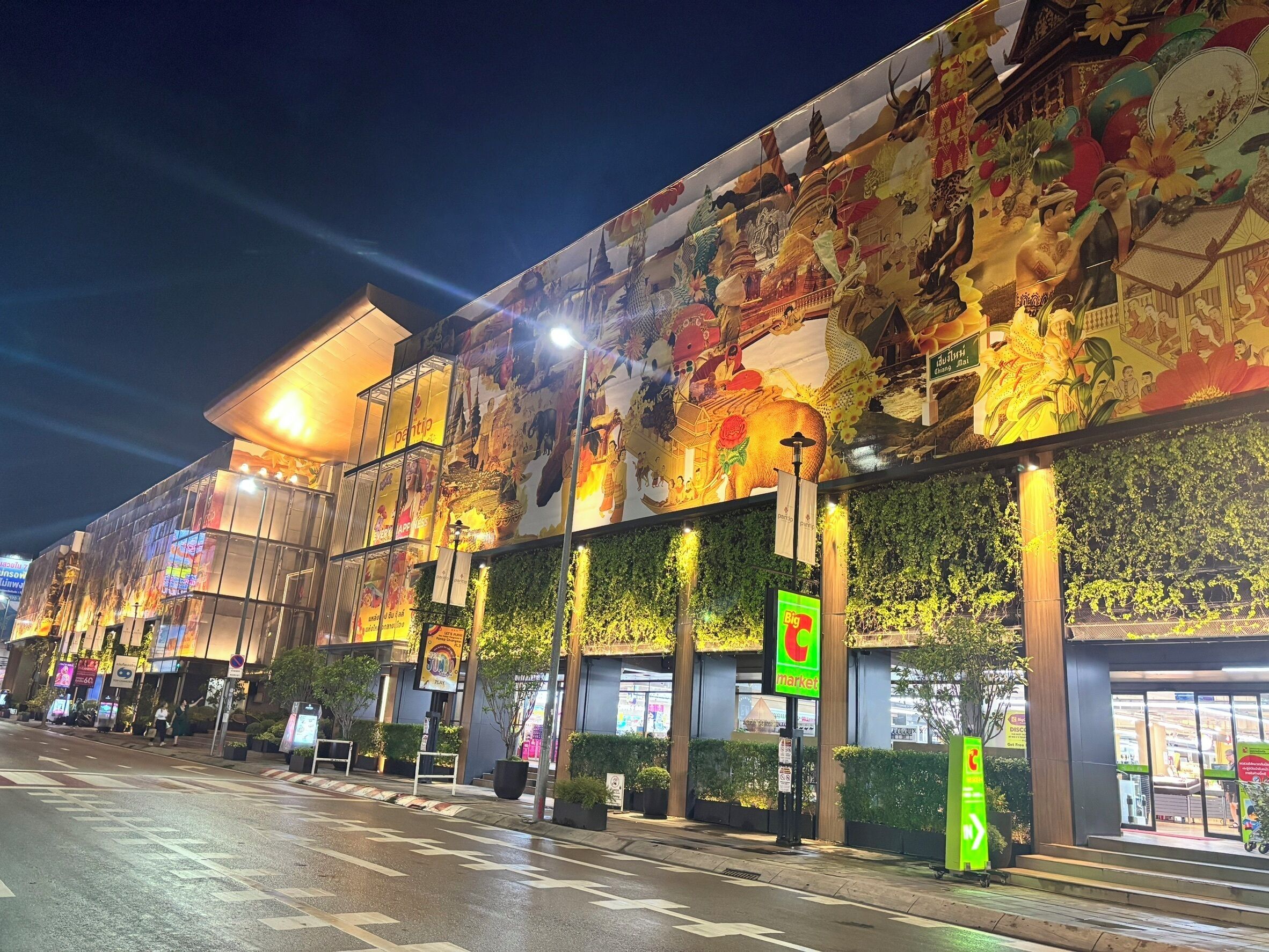 A building with a large mural, a market sign, and a green directional sign.