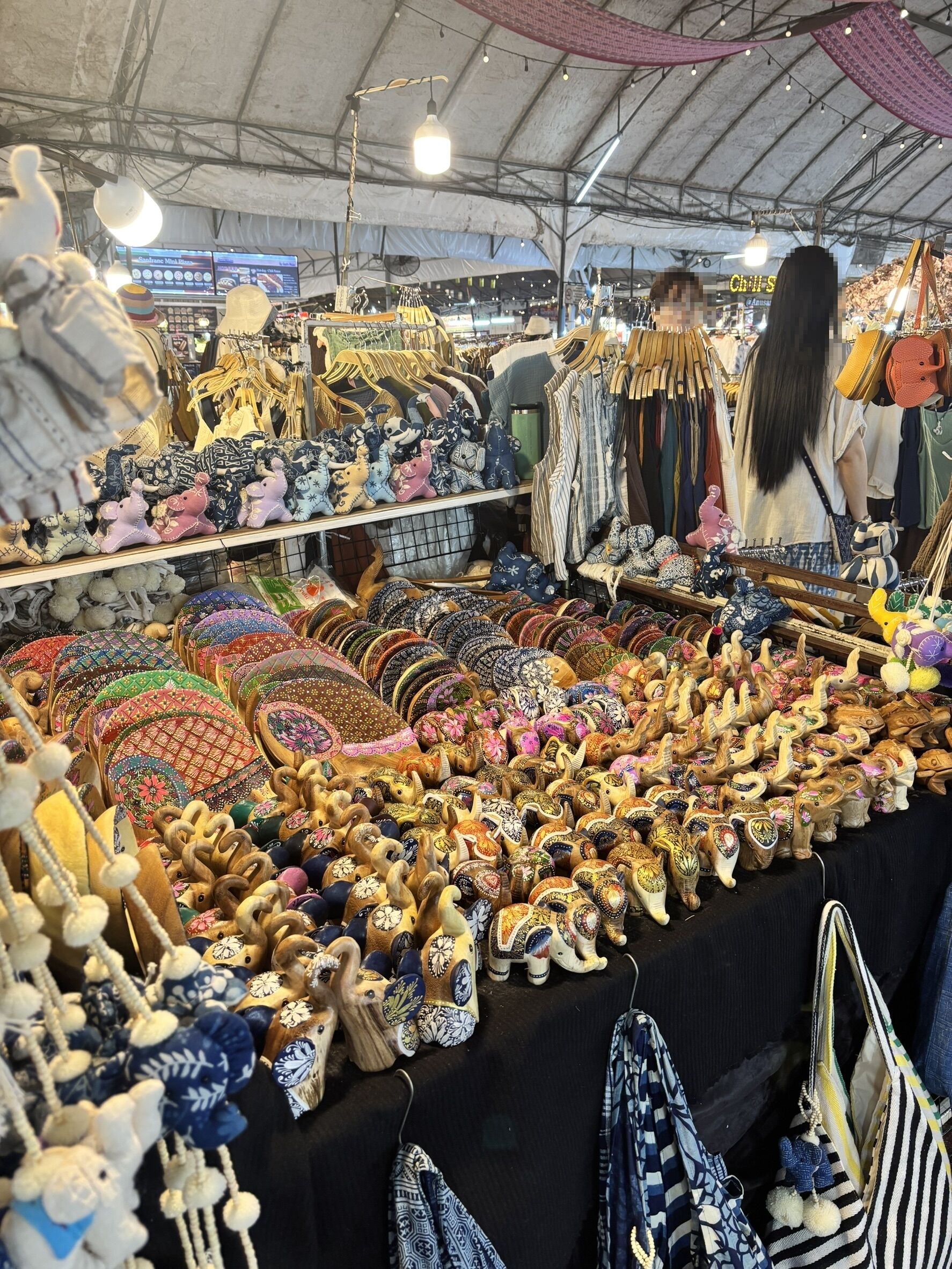 A market stall with various items including bags, plush toys, and textiles.