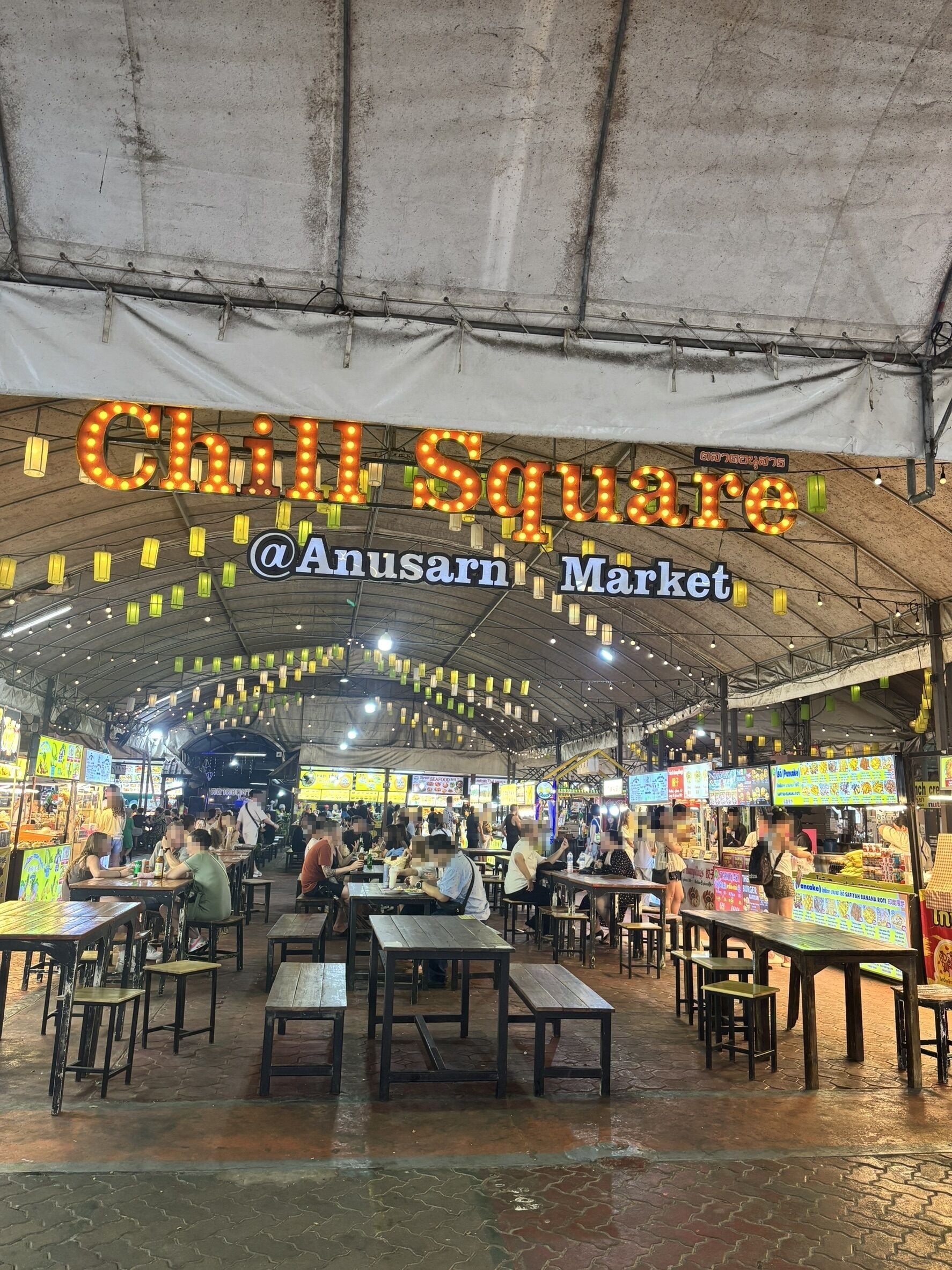 An indoor market with tables and chairs, and a sign overhead.