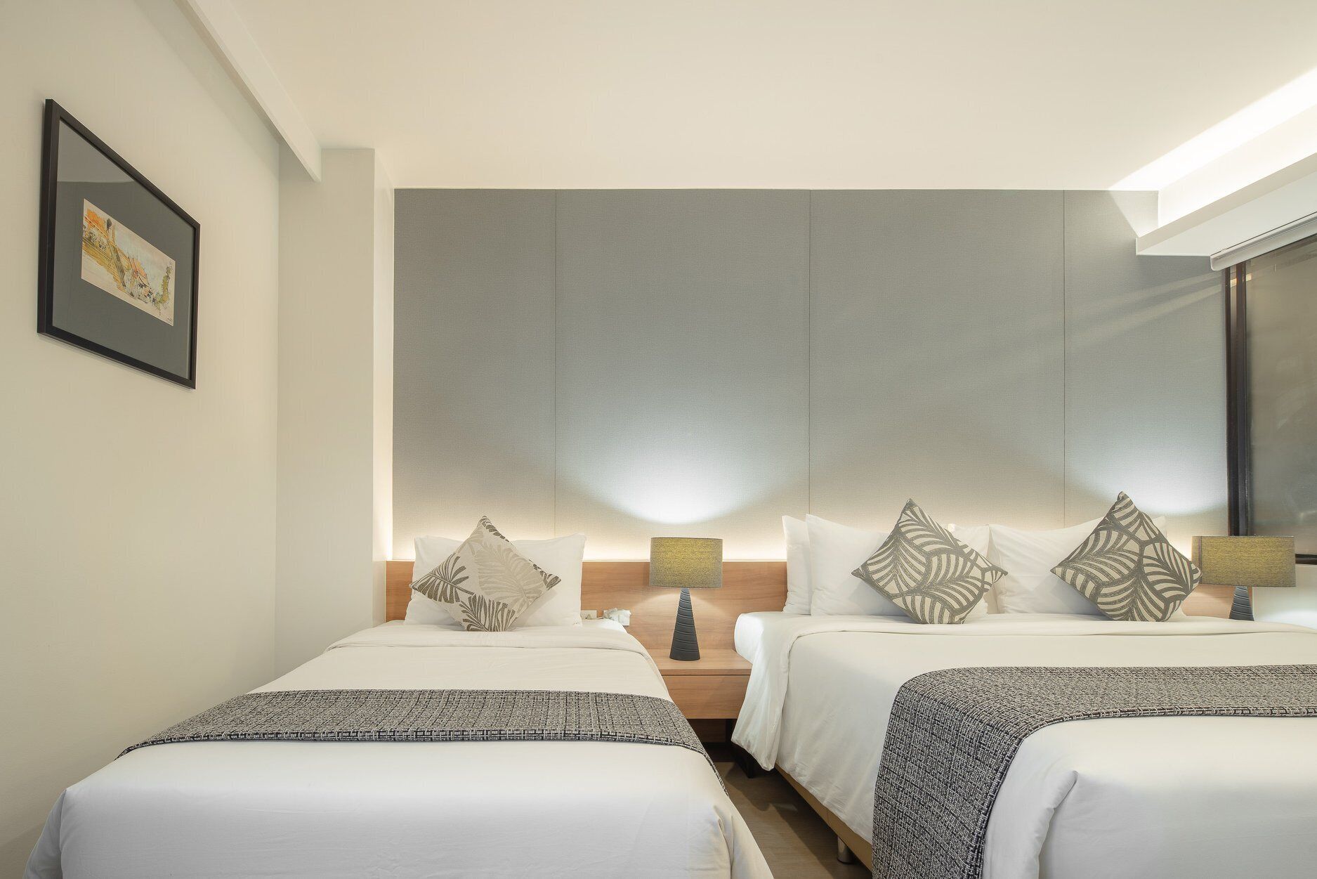 Ein Hotelzimmer mit zwei Betten, einem großen Spiegel und einem gerahmten Bild an der Wand.
