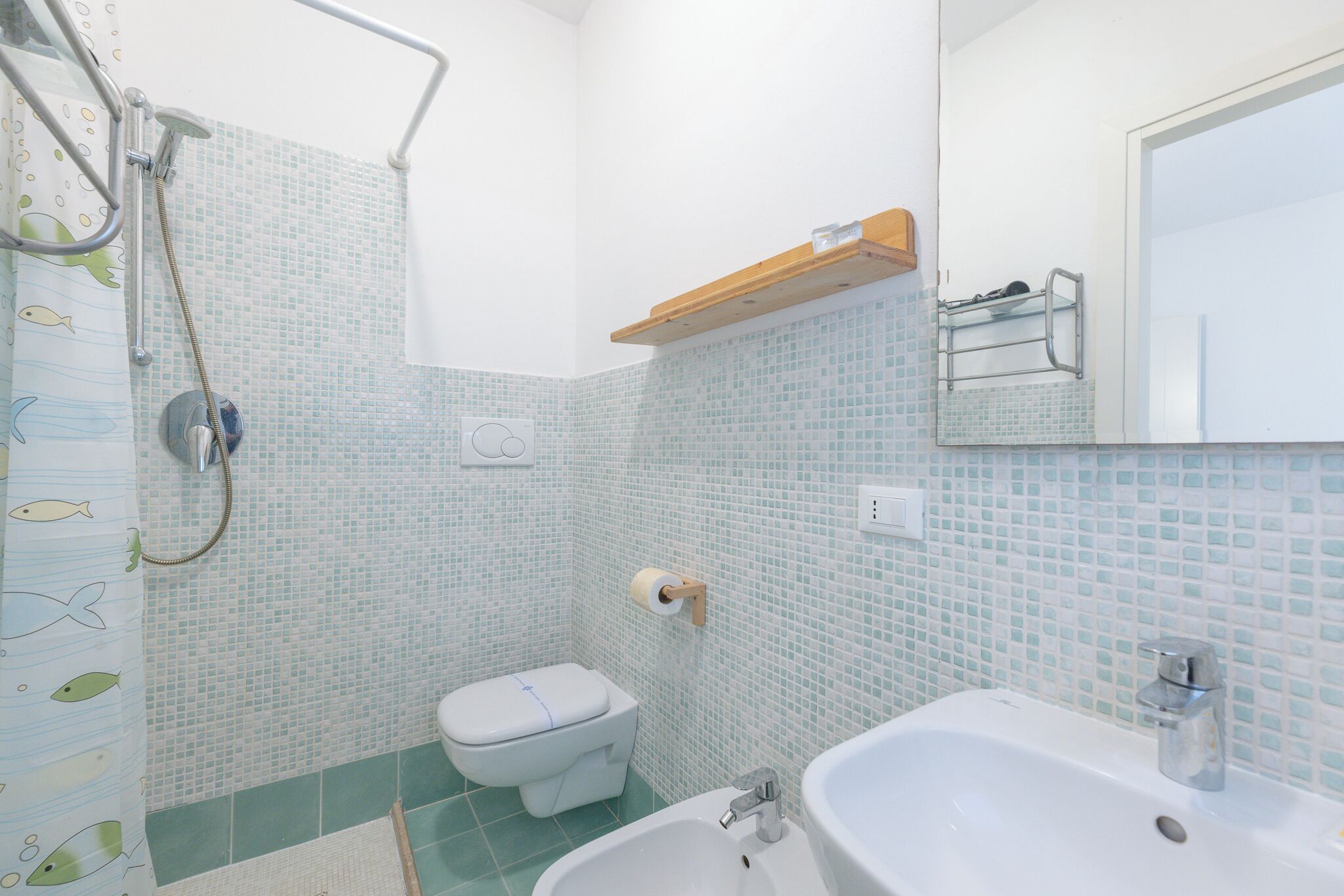 A bathroom with a shower, toilet, sink, and a mirror.