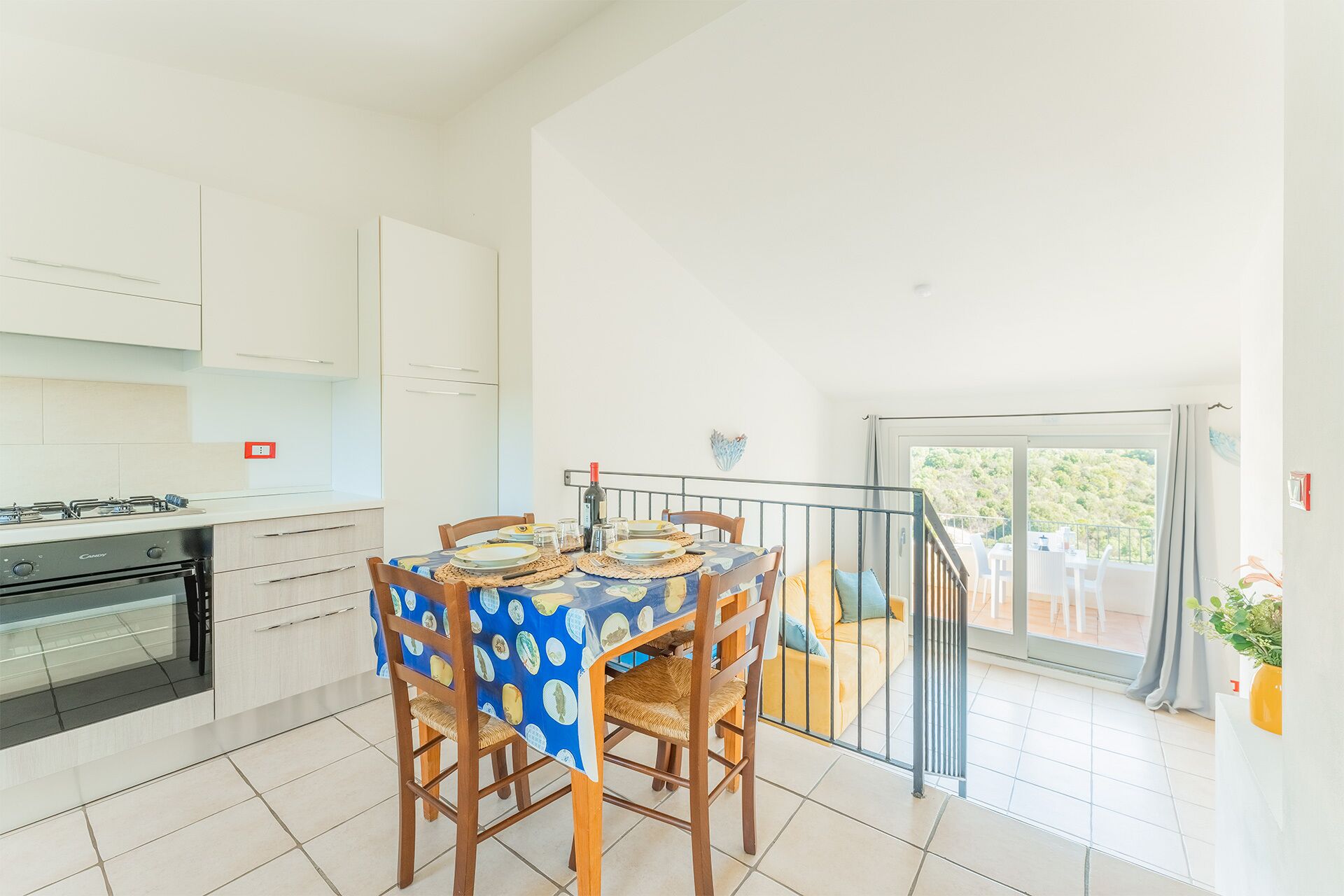 Una cocina moderna con armarios blancos, una estufa a gas y un comedor con una mesa dispuesta para cuatro.