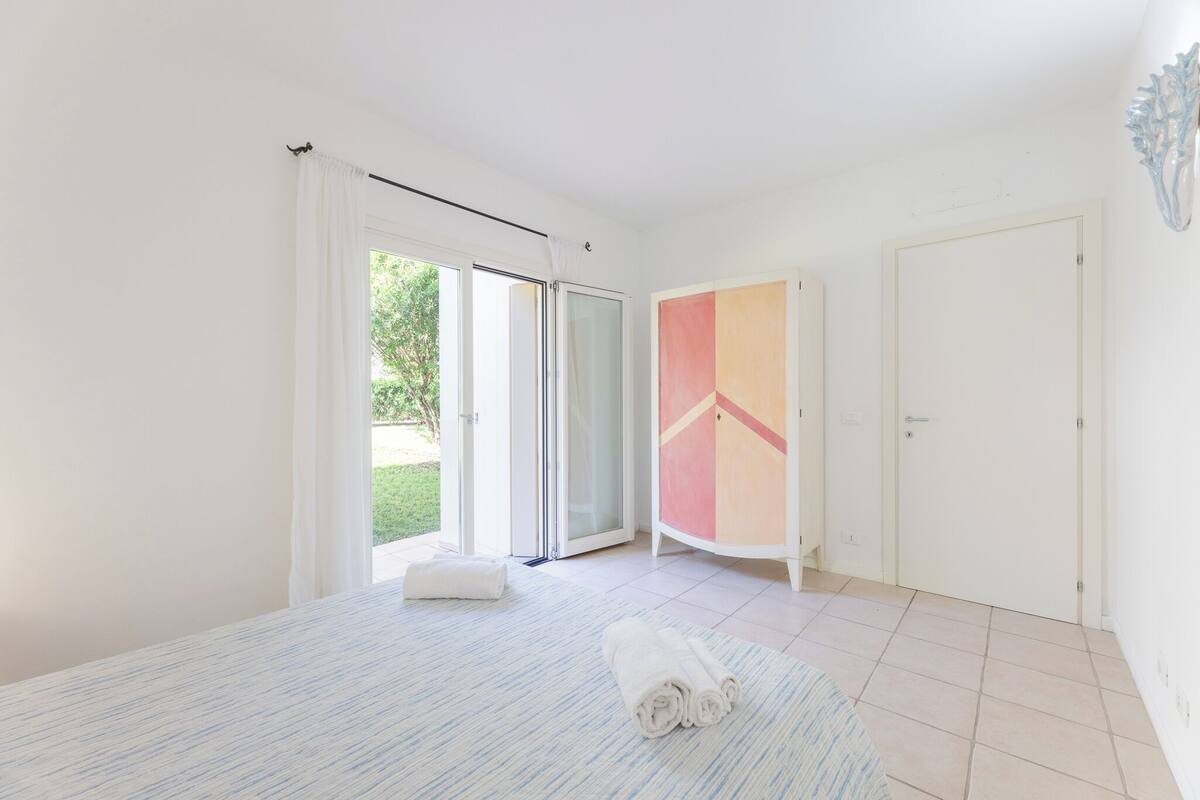 Une chambre avec un lit, une salle de bain avec une douche et une porte donnant sur un balcon.