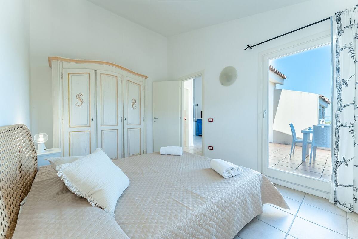 Une chambre avec un grand lit, une armoire et une vue sur l’extérieur.