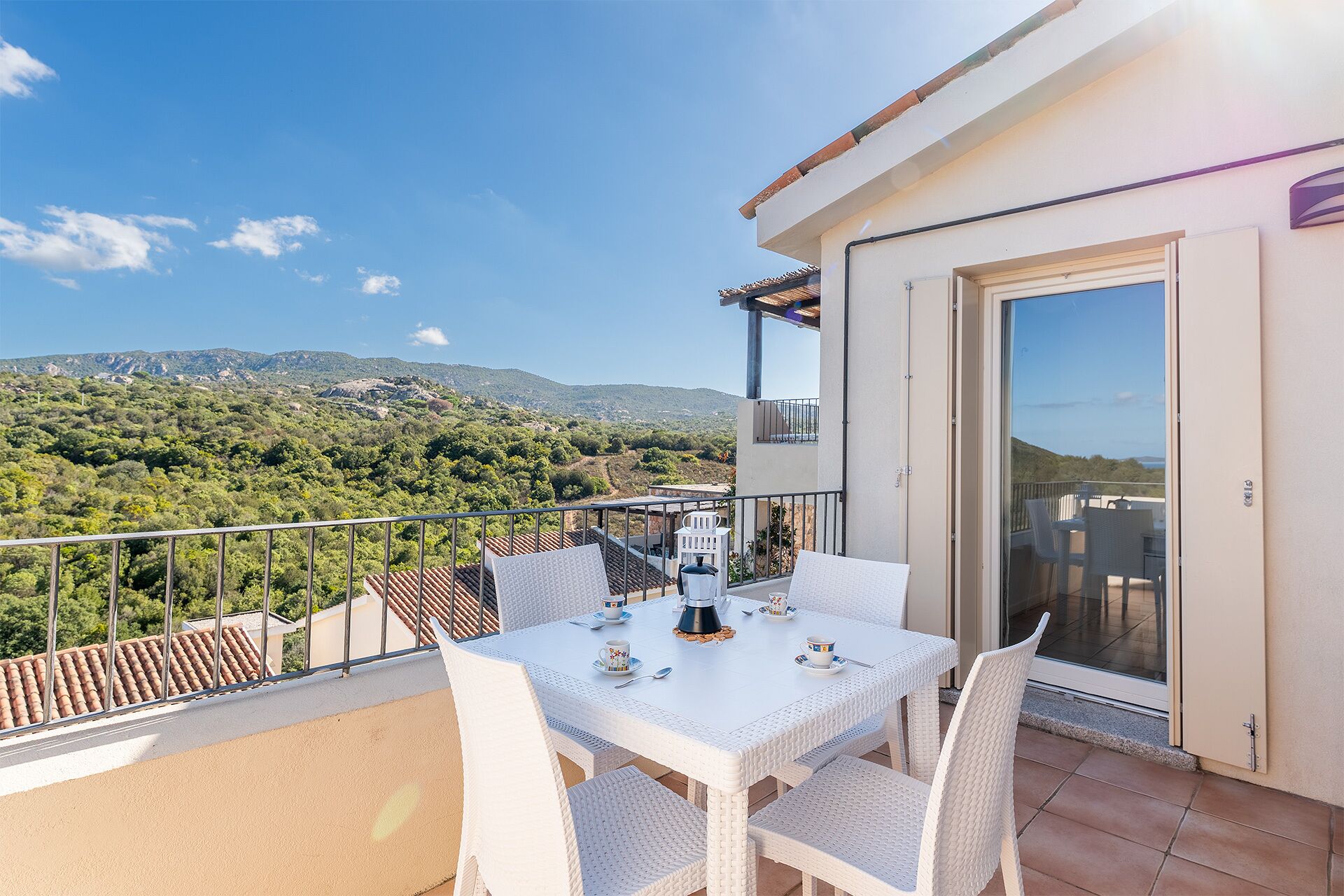 Un balcon avec une table et des chaises, donnant sur un paysage montagneux.