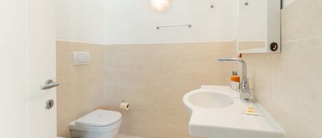 Un baño pequeño y moderno con inodoro, bidé y lavabo.