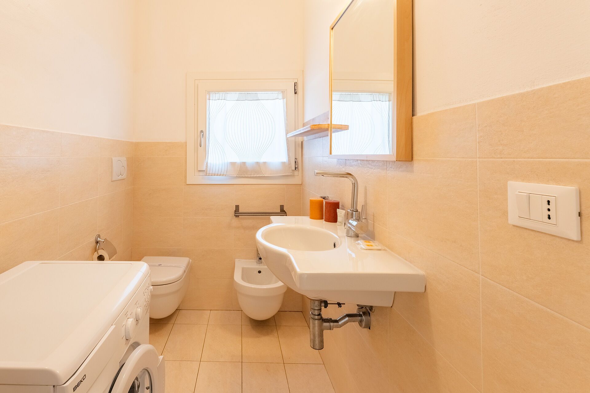 A compact bathroom with a toilet, bidet, and a washing machine.