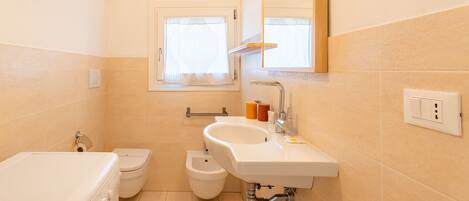 A compact bathroom with a toilet, bidet, and a washing machine.