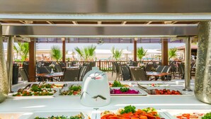Un buffet proposant une variété de plats, des tables en plein air et une vue sur la mer.
