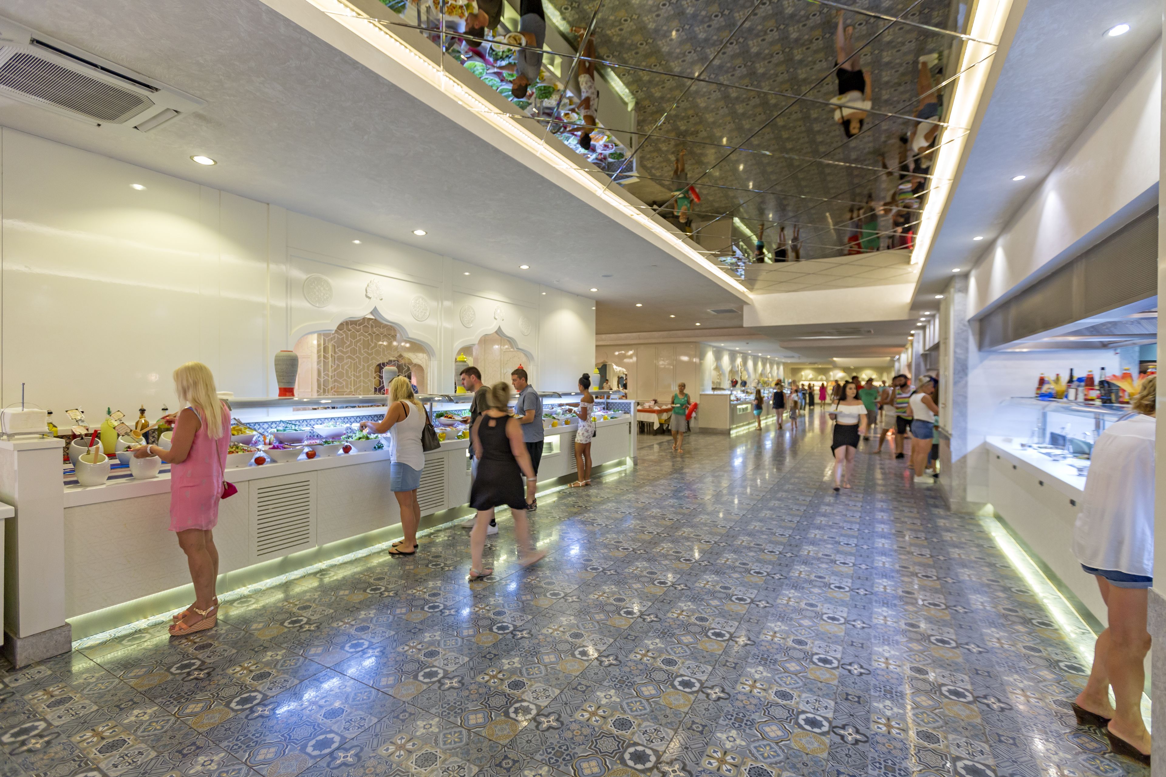 A spacious atrium with a tiled floor, multiple food counters, and a high ceiling with hanging decorations.