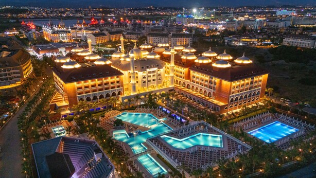 Un grand hôtel doté de plusieurs piscines, d’une cour intérieure et offrant une vue sur le paysage urbain environnant la nuit.