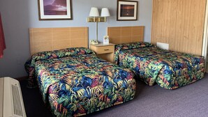 Een hotelkamer met twee bedden, een nachtkastje, een lamp en twee ingelijste foto’s aan de muur.