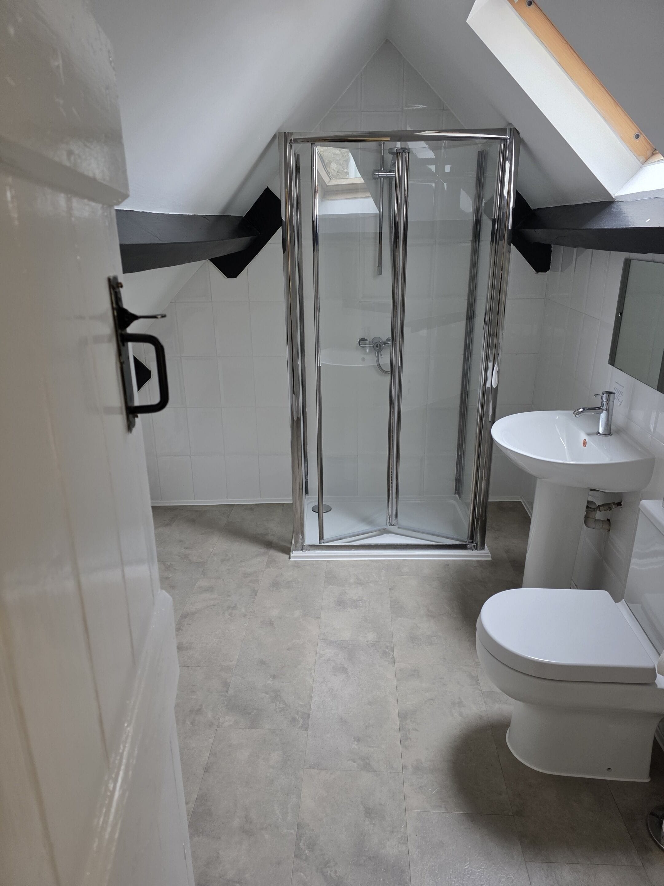 Un bagno moderno con box doccia in vetro, lavandino bianco e water.