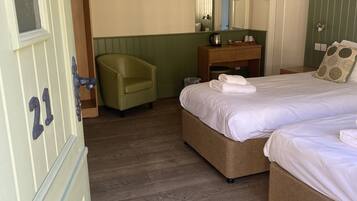 A hotel room with a bed, a chair, a vanity, and a small bathroom.