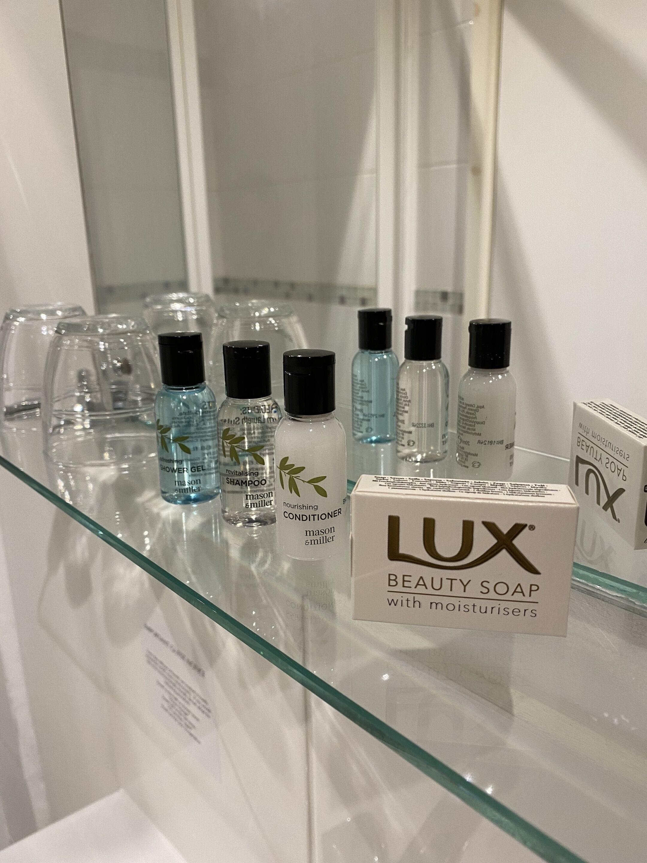 En hylla i badrummet med olika produkter för personlig hygien, inklusive Lux Beauty-tvål, duschgel och schampo.