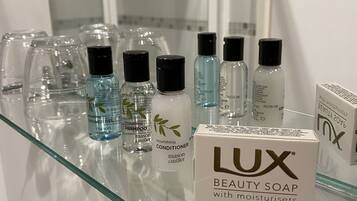 A bathroom shelf with various personal care products including Lux Beauty Soap, shower gel, and shampoo.