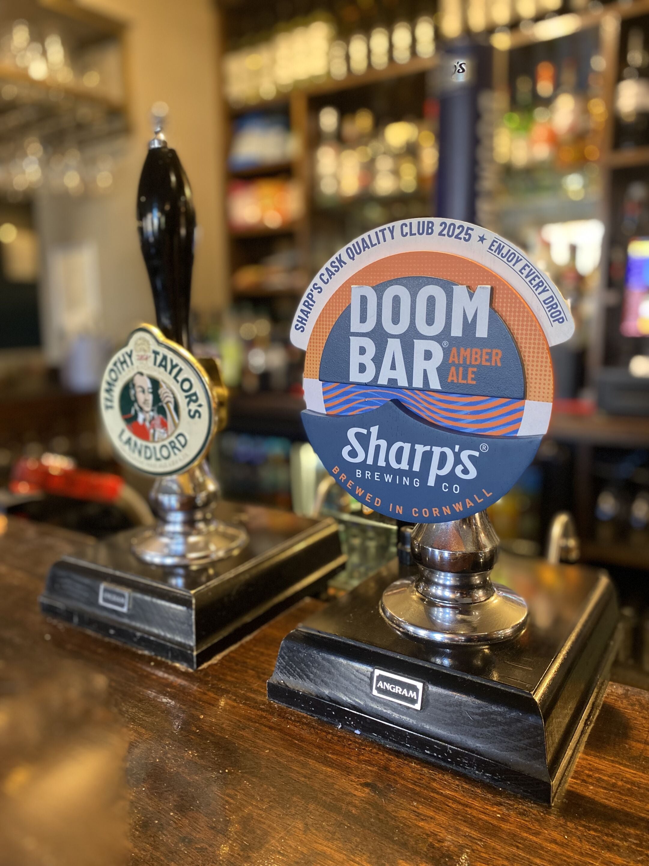 Un bar con dos grifos, uno etiquetado como 'Timothy Taylor's Landlord' y el otro 'Doom Bar Amber Ale'.