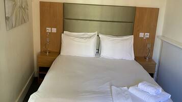 Una habitación de hotel con una cama grande, dos mesitas de noche, un cabecero de madera y una obra de arte colgada en la pared.