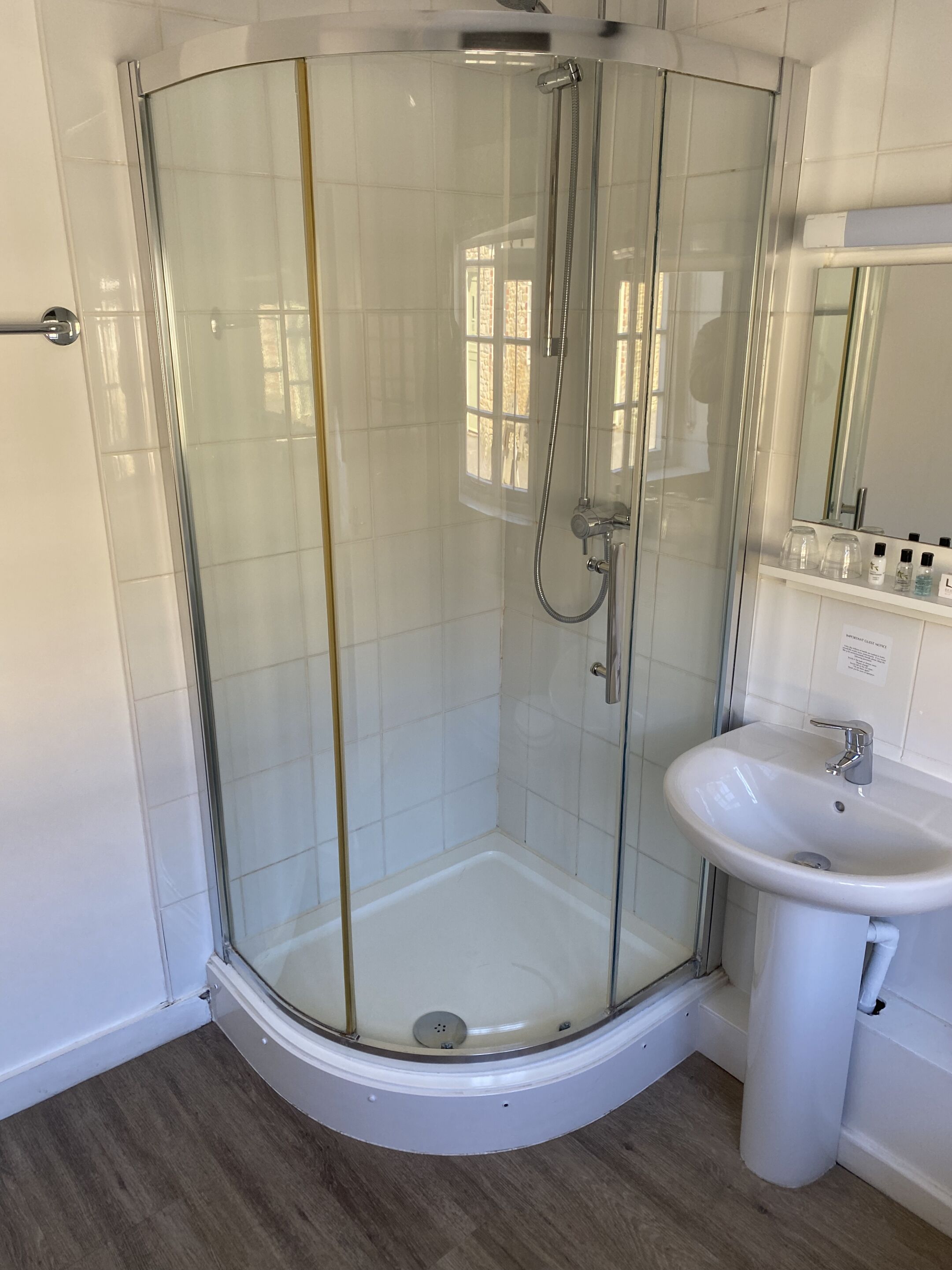 Un baño moderno con ducha de vidrio, un lavabo blanco y un espejo encima.