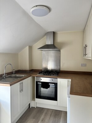 A kitchen with a stainless steel range hood, a built-in oven, and a double sink. - The New Inn Hotel (Lechlade)