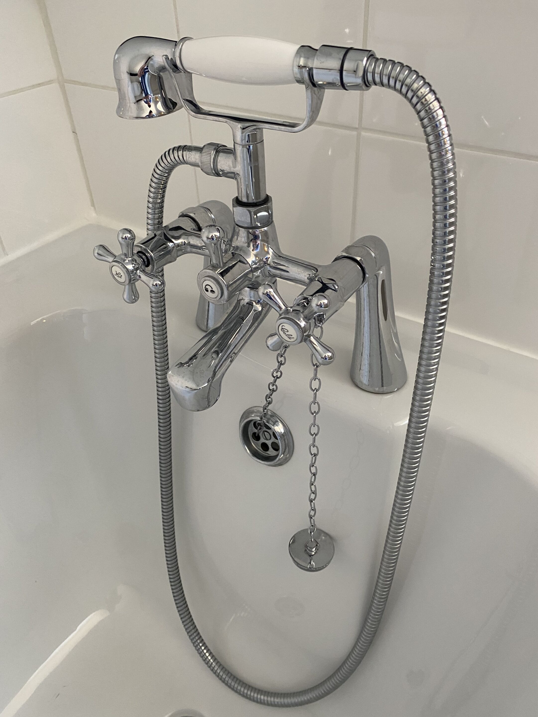A chrome bathroom fixture with a shower head, a handheld shower, and a flexible hose.