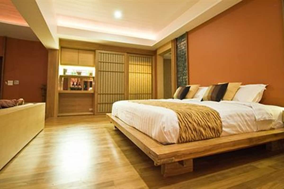 A bedroom with a large bed, wooden flooring, a built-in wardrobe, and a bedside table.