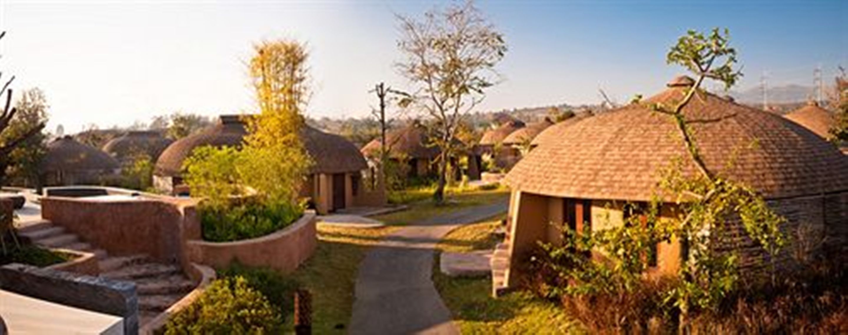 A series of dome-shaped huts with a pathway leading through them, surrounded by greenery.