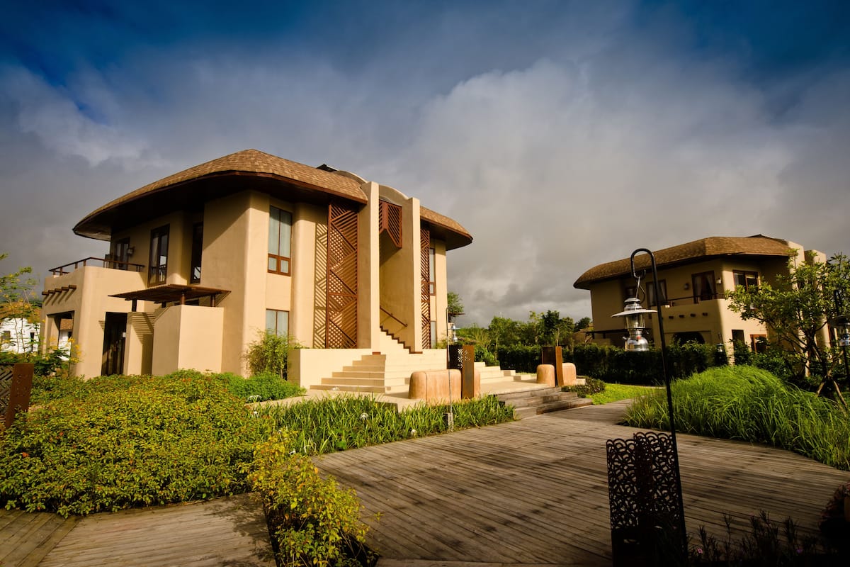 A modern building with a flat roof, large windows, and a wooden deck leading to the entrance.