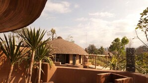 An outdoor seating area with wooden furniture and a thatched-roof structure. - Montis Resort (Pai)