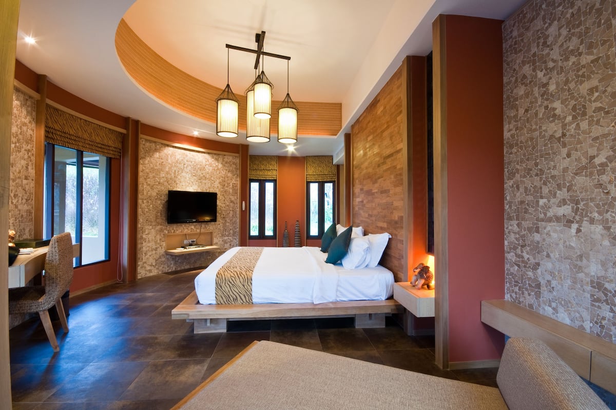 A modern bedroom with a large bed, a flat-screen TV, and a dining area with a table and chairs.