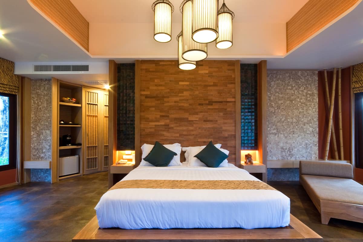 A modern hotel room with a large bed, bedside tables, a wardrobe, and a seating area.