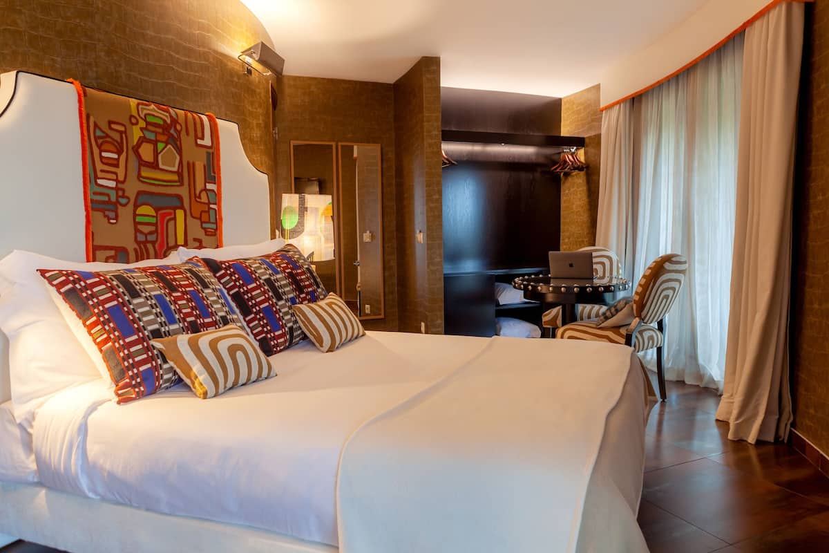 A hotel room with a large bed, a desk, and a chair.