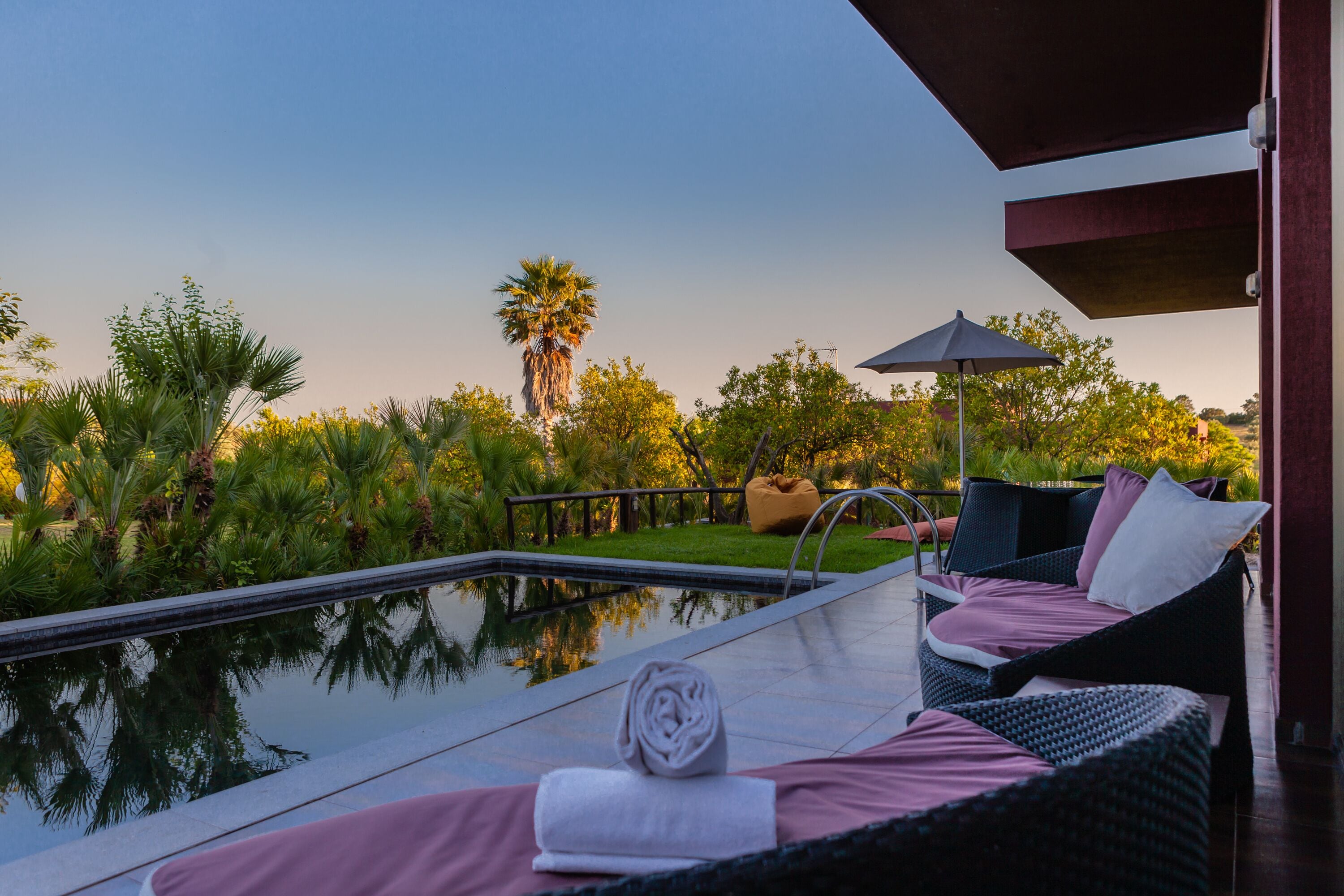 A poolside area with a lounge chair, a towel, and an umbrella.