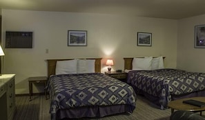 A hotel room with two beds, a nightstand with a lamp, a small table, and a chair. - Silver Spruce Resort (Wisconsin Dells)