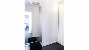 A narrow hallway with a mirror reflecting a room with a door and a window. - Hôtel Satellite (Brussels)