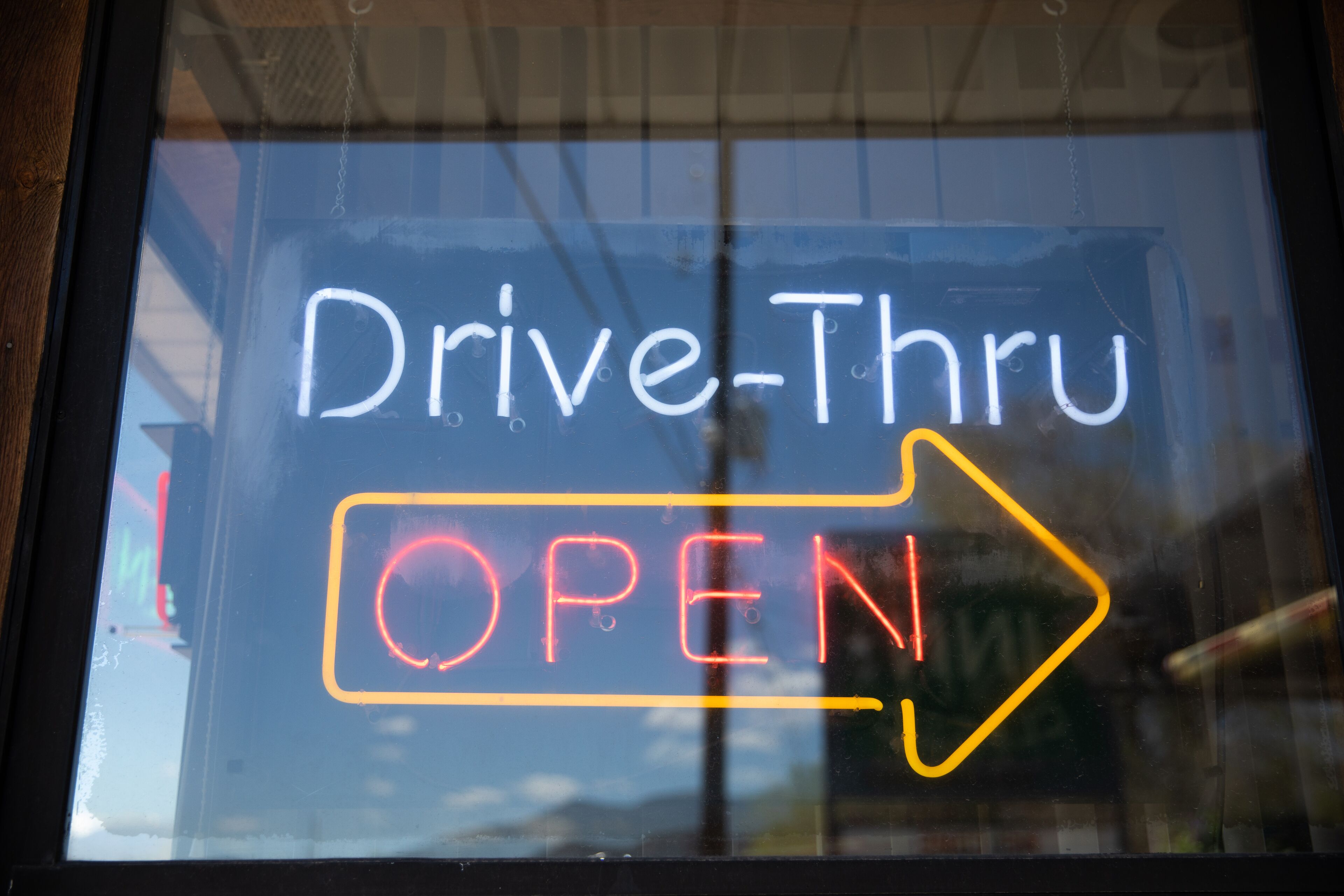 A window with a neon sign indicating a drive-thru is open.