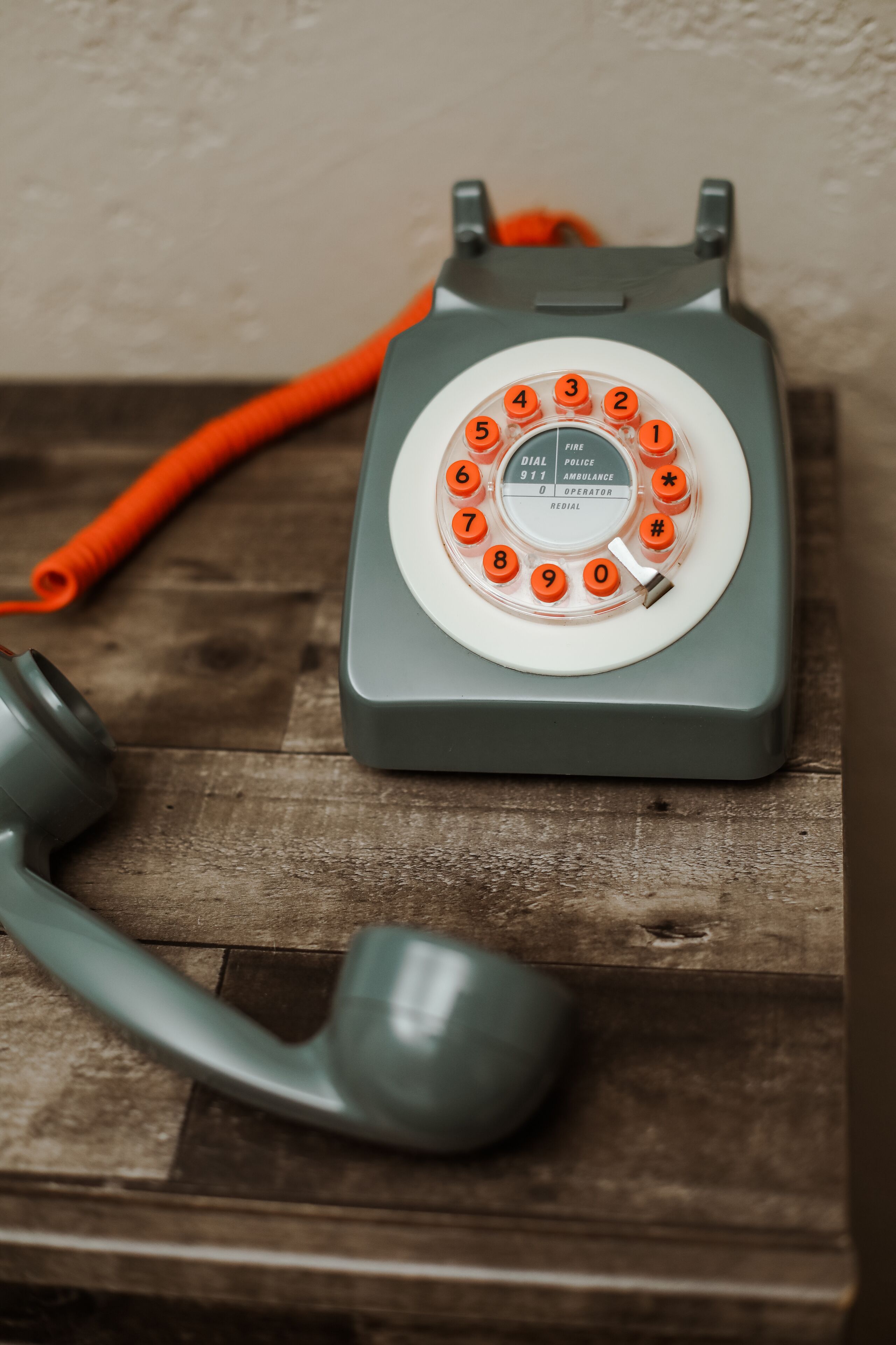 Un teléfono con dial rotativo y cable, sobre una superficie de madera.