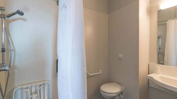 A small, compact bathroom with a shower, toilet, and sink.