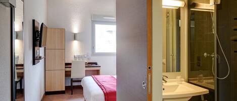 Ein Hotelzimmer mit Bett, Schreibtisch, Dusche und Badezimmer.
