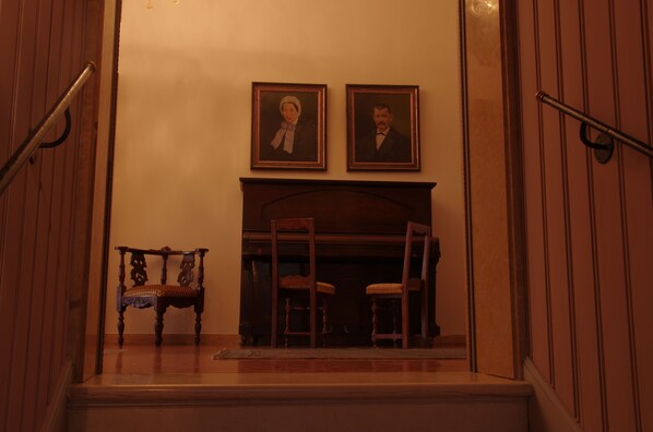 A staircase with a wooden bench and two framed portraits above a fireplace. - La Residenza 818 (Venice)