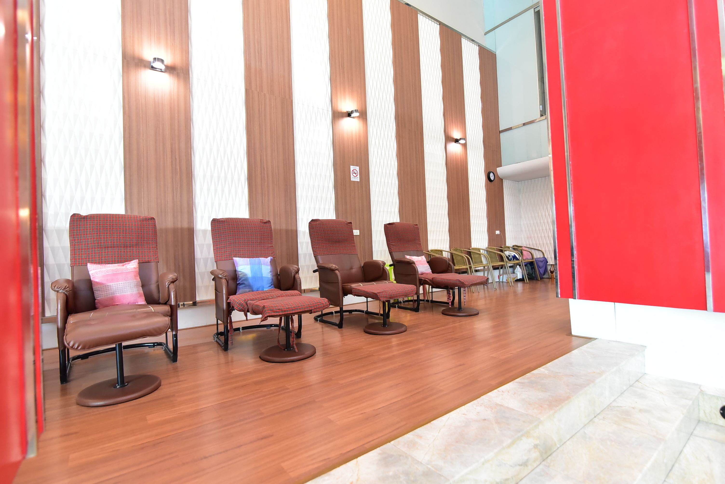 A row of leather chairs with cushions, a wooden floor, and a striped wall with lights.